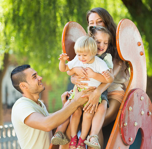 istock Smiling parents helping kids on slide 538038941