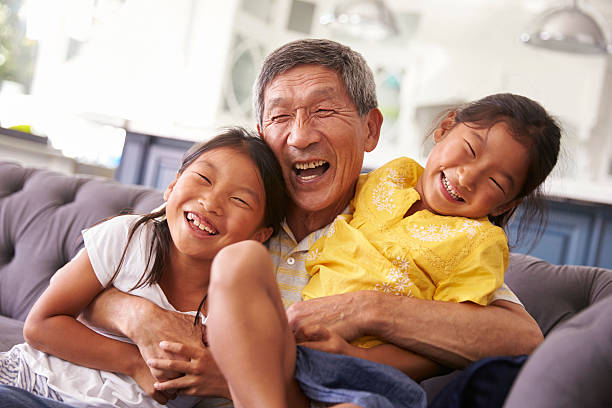 abuelo y nietas descanse en el sofá en casa - coreano oriental fotografías e imágenes de stock