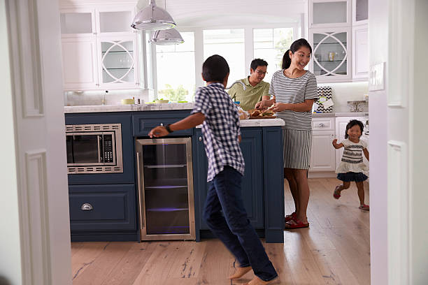 los padres preparar comida mientras los niños juegan en la cocina - atestado fotografías e imágenes de stock