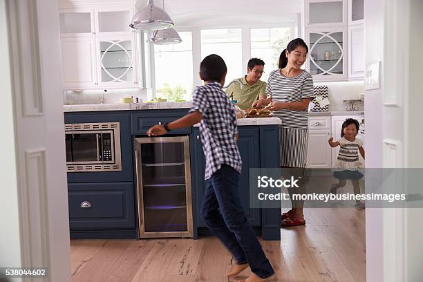 Parents Prepare Food As Children Play In Kitchen Stock Photo - Download Image Now - Family, Crowded, Busy