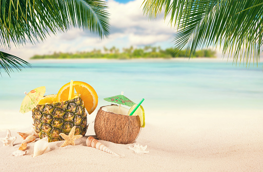 Sandy tropical beach with palm island and summer drinks