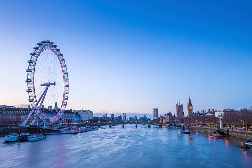 Skyline of London before sunrise with famous landmarks, Big Ben, Houses of Parliament, boat and clear blue sky - London, UK