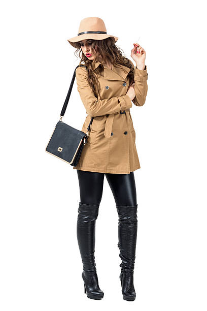 istock Young woman with hat and purse holding cigarette looking down. 538054336