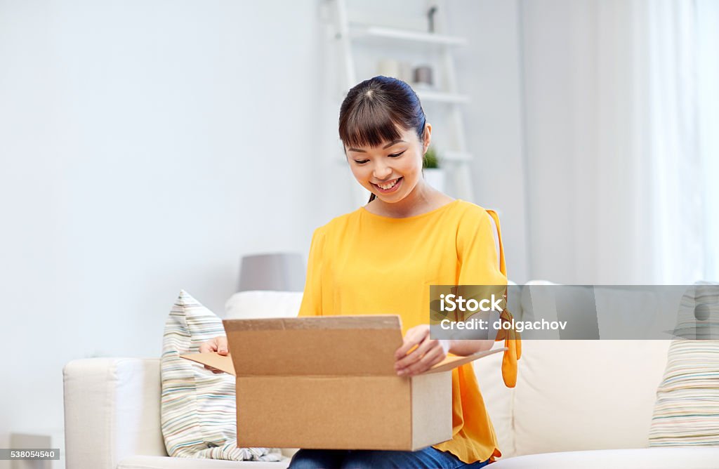 happy asian young woman with parcel box at home people, delivery, commerce, shipping and shopping concept - happy asian young woman with cardboard parcel box at home Box - Container Stock Photo