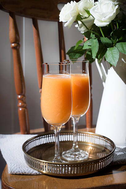 Two champagne flutes with cocktail and roses