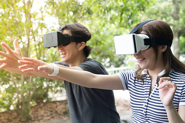 amigos divirtiéndose con consolas de realidad virtual - pantalla montada en la cabeza fotografías e imágenes de stock