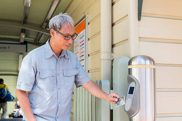 Mature Asian man tapping his Opal card at the exit of the train station. Sydney Australia.