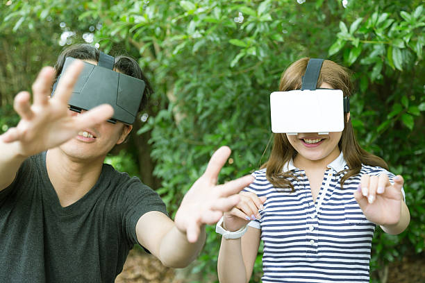 amigos divirtiéndose con consolas de realidad virtual - pantalla montada en la cabeza fotografías e imágenes de stock