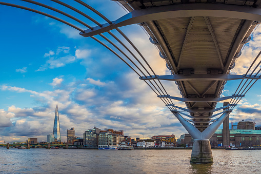 London's skyline taken under the Millennium Bridge at sunset with Shard skyscraper and beautiful sky and clouds - London, UK