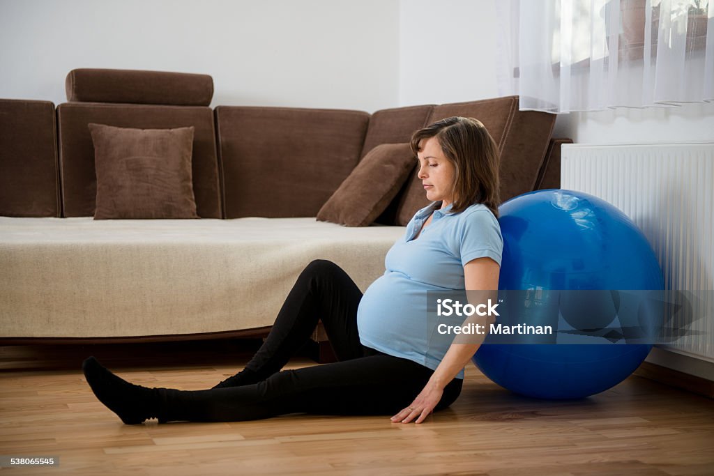 Exercise at pregnancy Pregnant woman relaxing after exercising with fit ball at home 2015 Stock Photo