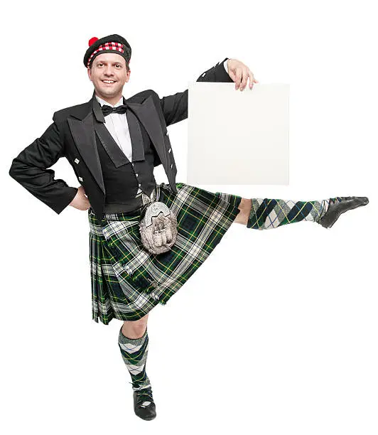 Young man in clothing for Scottish dance with empty banner isolated