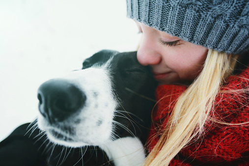 Woman hugging a dog in a winter day.