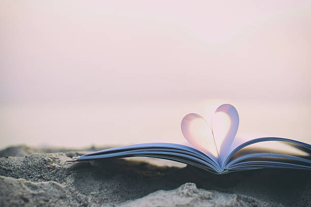 istock Close up heart shape from paper book on sand background 538068480
