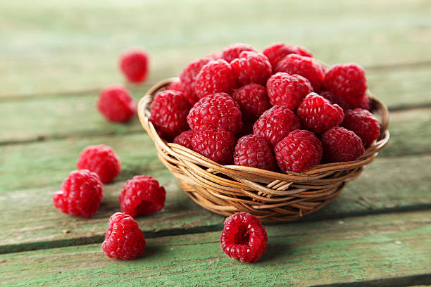 istock Raspberries in basket on green wooden background 538069977