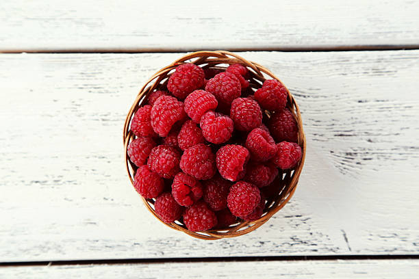istock Raspberries in basket on white wooden background 538070231