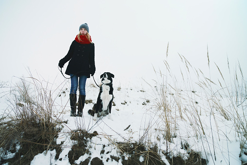 Woman playing with the dog in fresh snow.