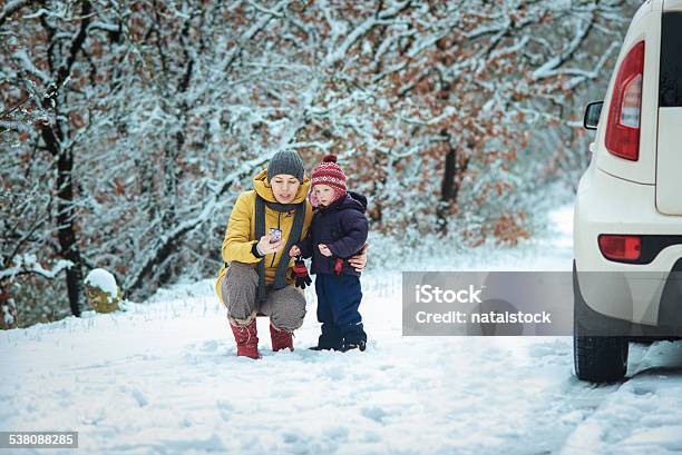 Woman With A Child On The Winter Road Stock Photo - Download Image Now - 2015, Adult, Car