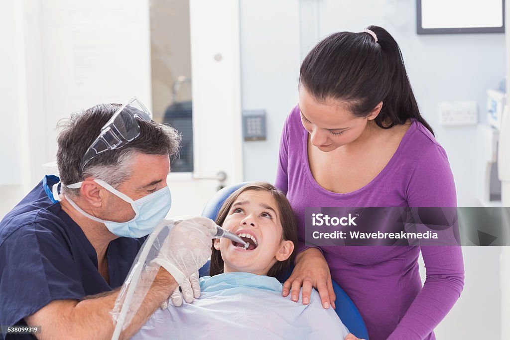 Pediatric dentist examining young patient with her mother Pediatric dentist examining young patient with her mother in dental clinic 10-11 Years Stock Photo