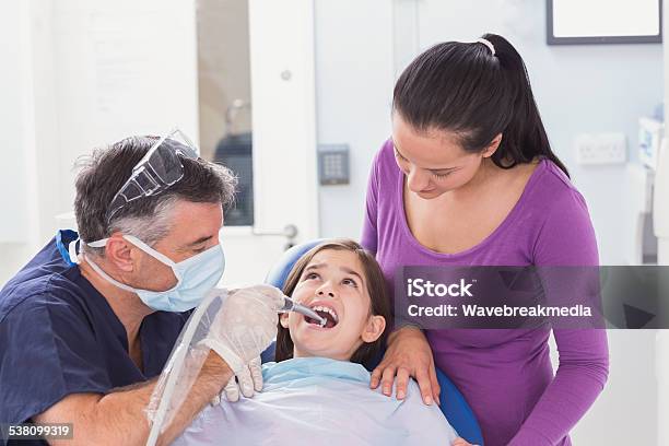 Pediatric Dentist Examining Young Patient With Her Mother Stock Photo - Download Image Now