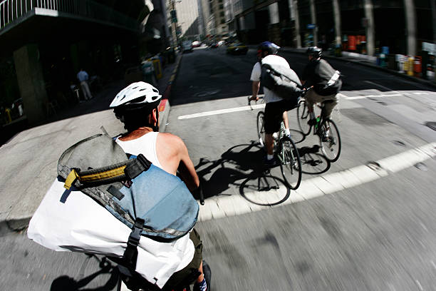 Three male bike messengers cross a busy street in downtown San Francisco, California, USA.