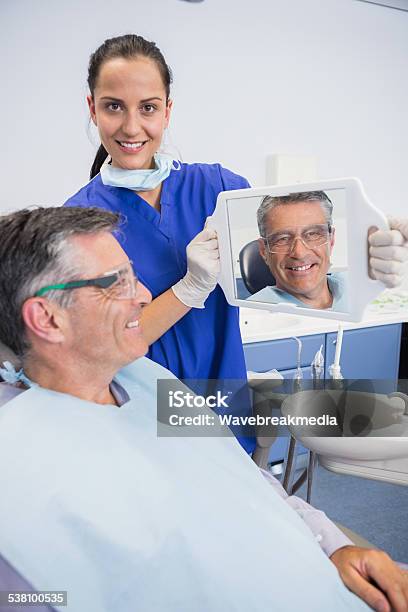 Smiling Dentist Showing Teeth Of Her Patient With A Mirror Stock Photo - Download Image Now