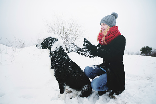 Woman playing with the dog in fresh snow.