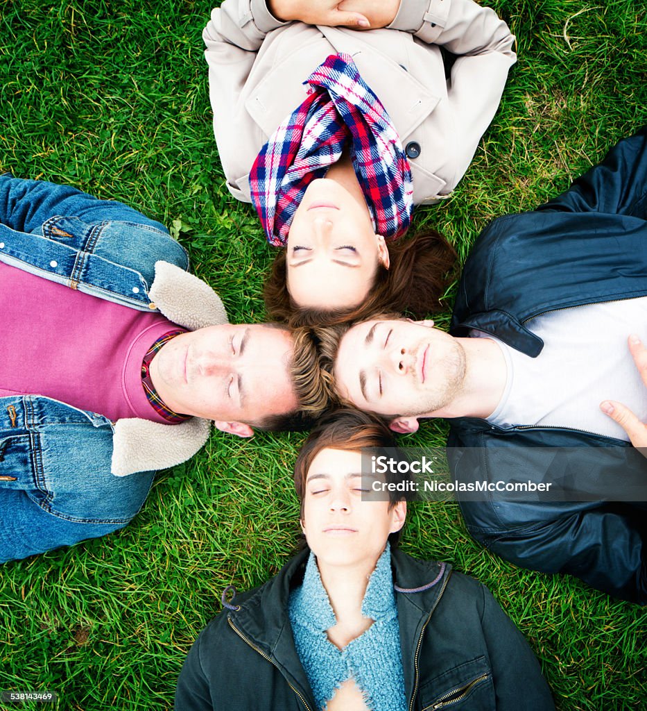 Four friends napping on the lawn heads touching Four friends napping on the lawn heads touching. Shot from above. 20-29 Years Stock Photo