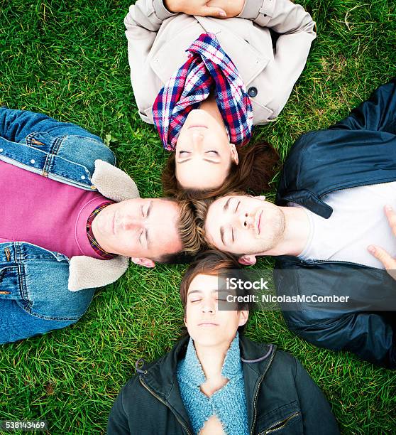 Four Friends Napping On The Lawn Heads Touching Stock Photo - Download Image Now - 20-29 Years, 2015, Adults Only
