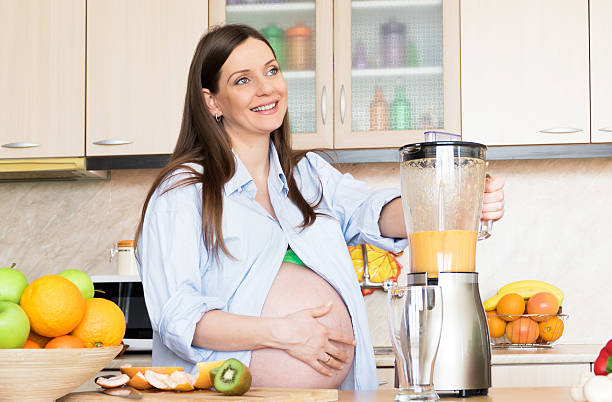 istock Pregnant woman making fresh orange juice 538143635