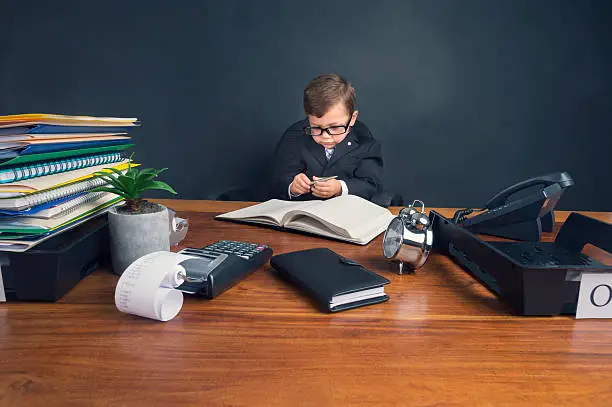 Photo of Young boy dressed in suit working at desk.