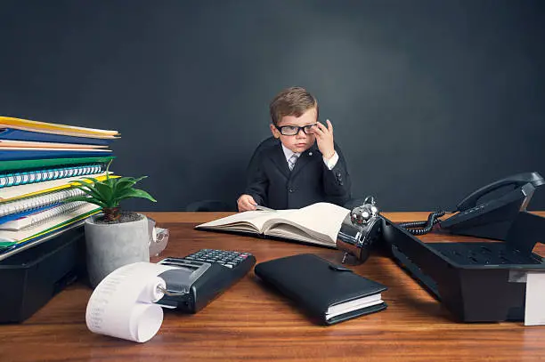 Photo of Young boy dressed in suit working at desk.