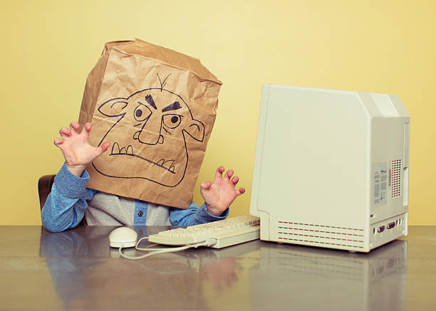 Internet Troll is Mean at the Computer This young person is hiding behind a false identity and is acting like a troll online. Stop bullying. ugliness photos stock pictures, royalty-free photos & images