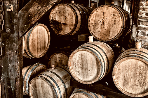 Wine or Rum Stored in Oak Barrels.  POV photo with focus on closest barrel.  Wood tones and copy space.  Leica camera photograph.