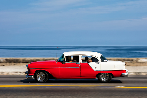 Havana, Сuba - April 16, 2016: Blue vintage American car speeding along the Malecon in Havana, Cuba, motion blur, Caribbean Sea is visible in the background, 50 megapixel image.