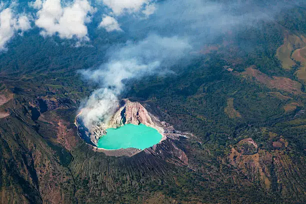 Aerial photo of active volcano Ijen in East Java - largest highly acidic crater lake in world with turquoise sulphuric water. Site of sulfur mining. Famous travel destinations of Indonesian islands.