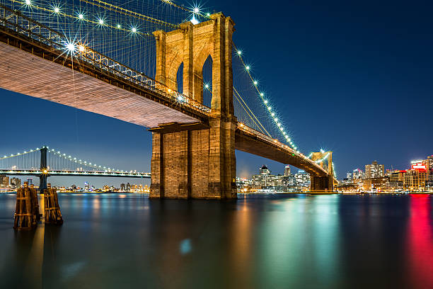 brooklyn bridge bei nacht beleuchtet - new york city brooklyn bridge night stock-fotos und bilder