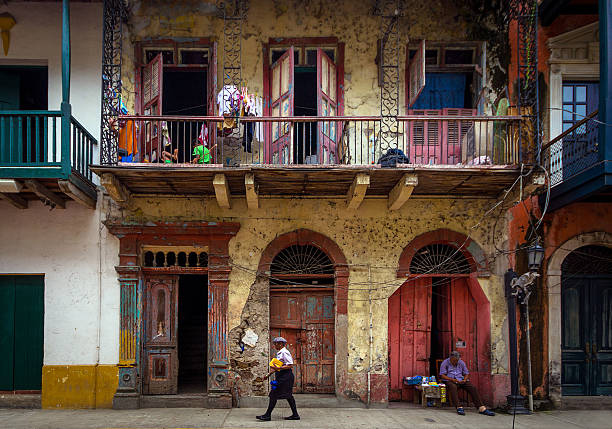 Panama City, Panama - September 12, 2013: Image of a woman walking the streets and a vendor sleeping, street image in historic Casco Viejo district of Panama City, Panama. 