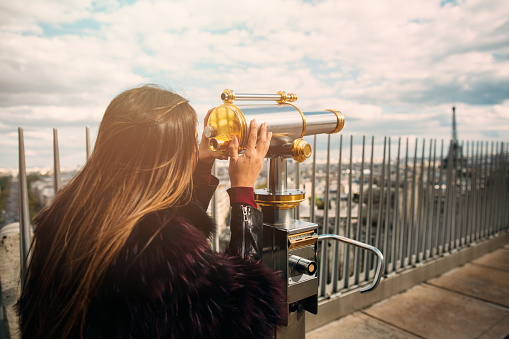 Young beautiful woman looking at the Eiffel Tower on observation deck in Paris.