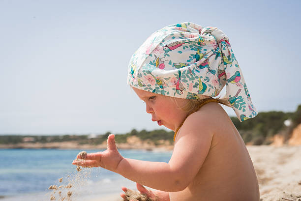 Baby girl playing in sand stock photo