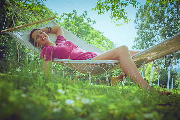 junge sorglos frau entspannt sich in einer hängematte im garten - formal garden flower bed women grass stock-fotos und bilder