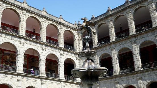 Mexico City, Mexico - January 02, 2013: Inner courtyard of the National Palace, one of the oldest and finest buildings in the city. It is the official home of the president and it is located at the Zócalo Square. Corridors with beautiful panels of Diego Rivera tell the history of the country and in particular the fountain with a winged horse statue. 