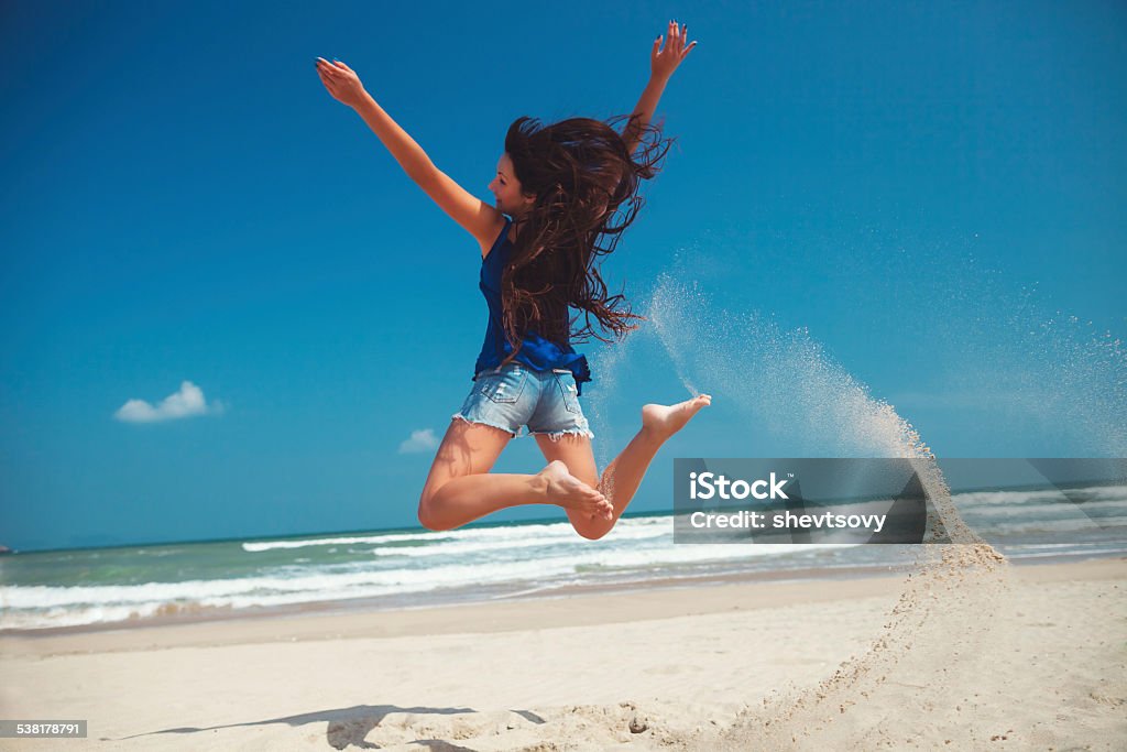 happy girl jumping on the beach happy girl jumping on the beach  with blue sky background 2015 Stock Photo