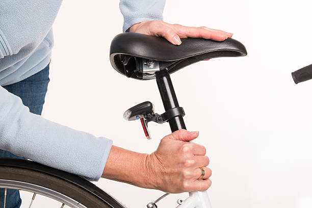 Woman sets height of  bicycle saddle before cycling