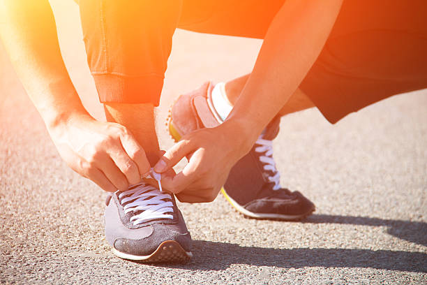 istock close up man runner tying shoelaces 538183314