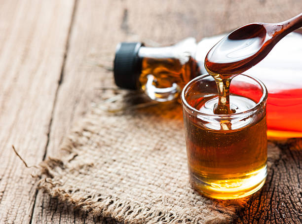 maple syrup in glass bottle on wooden table maple syrup in glass bottle on wooden table maple syrup stock pictures, royalty-free photos & images