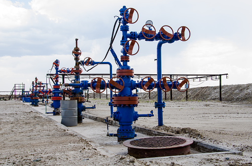 Group of wellheads and pipeline. Oilfield with sand ground. Oil and gas concept.