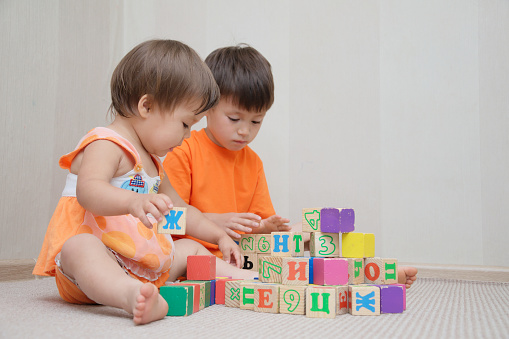 Brother and little sister constructing together with toy cubes
