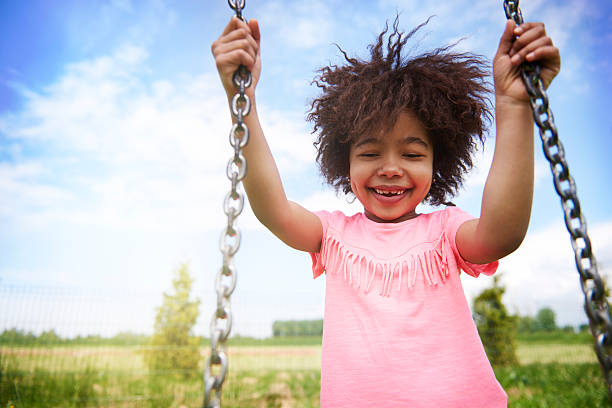 afrykańska dziewczyna uwielbia kołyszący się na plac zabaw - child swinging playground african descent zdjęcia i obrazy z banku zdjęć