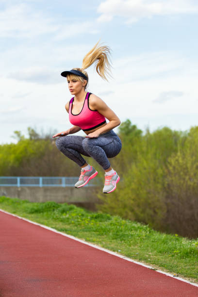 encantados de mujer saltar en el aire. - running track women running spring fotografías e imágenes de stock