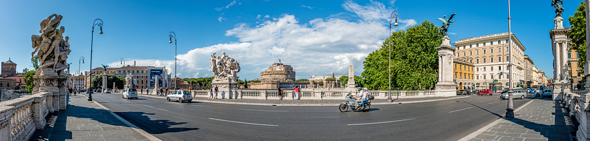 Rome, Italy - June 6, 2016: Wide angle panorama with tourists walking on Ponte Vittorio Emanuele II, in the background Castel Sant'Angelo (Mausoleum of Hadrian), St. Angelo Bridge and River Tiber
